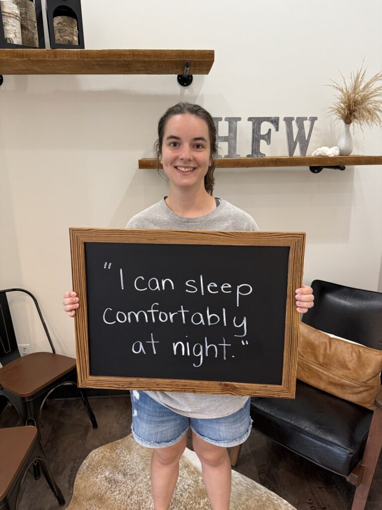 A Health From Within patient holding a chalkboard that reads: I can sleep comfortably at night.