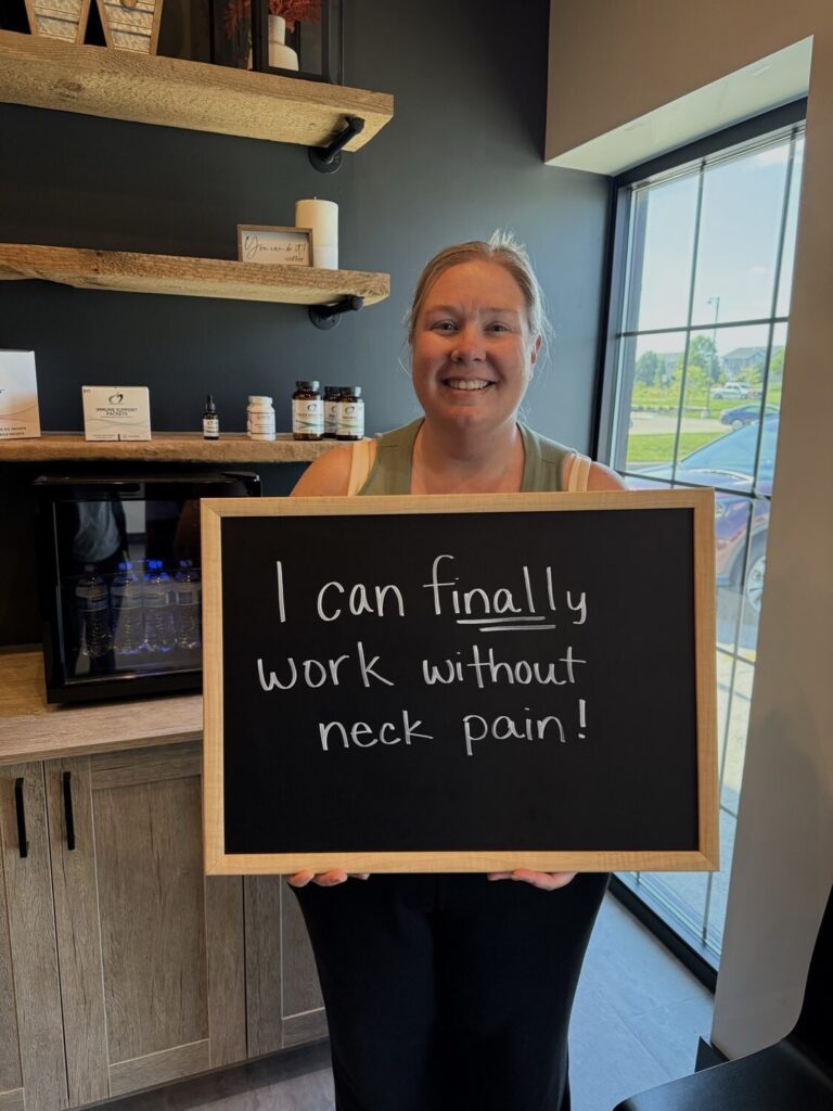 A Health From Within patient holding a chalkboard that reads: I can finally work without neck pain!