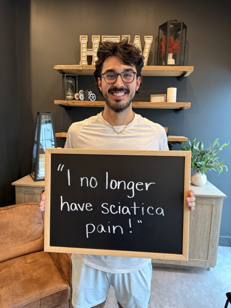 A Health From Within patient holding a chalkboard that reads: I no longer have sciatica pain!
