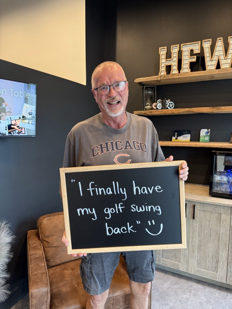 A Health From Within patient holding a chalkboard that reads: I finally have my golf swing back.